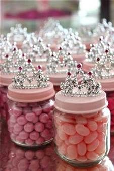 candy jars filled with pink and white candies, topped with tiara crowns on top