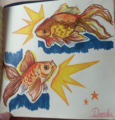 an open book with two drawings of goldfish and starbursts on it