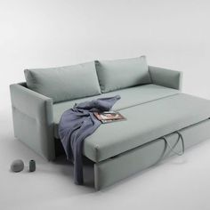 a couch that is sitting on the ground with a blanket over it's back