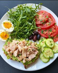 a white plate topped with meat, vegetables and eggs