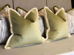 three green pillows sitting on top of a bed next to two white and gray pillows