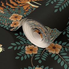 a roll of paper on top of a wallpaper with flowers and leaves in the background