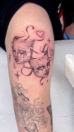 a woman's leg with tattoos on it and an image of two masks in the middle