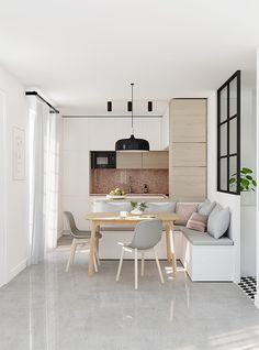 a white kitchen and dining room with an l shaped table in the center, along with two gray chairs