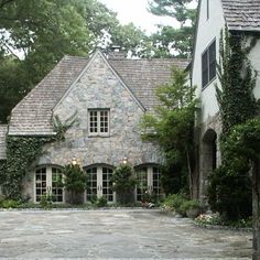 a large stone house surrounded by greenery and trees in front of it's entrance