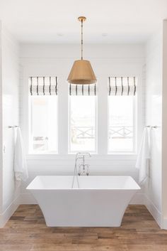 a large white bath tub sitting under two windows