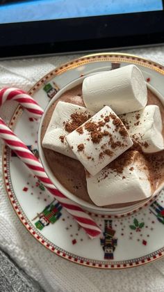 hot chocolate with marshmallows and peppermint on a plate next to a candy cane