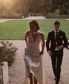 a woman in a white dress walking next to a man in a suit