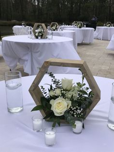 a centerpiece with white flowers and greenery on a table