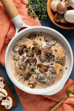 a bowl of soup with mushrooms in it next to other foods and utensils