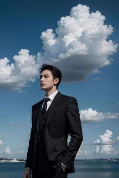 a man in a suit and tie standing by the water with clouds above his head