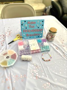 a table topped with lots of crafting supplies on top of a white table cloth