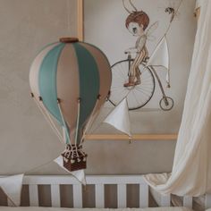 a baby's crib with a hot air balloon hanging from the ceiling next to it