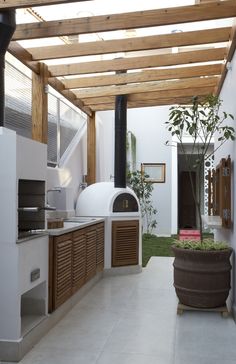 an outdoor kitchen is shown with wood and white walls, along with potted plants