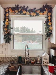 a kitchen sink sitting under a window covered in christmas decorations