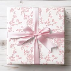 a gift wrapped in pink and white paper with a bow