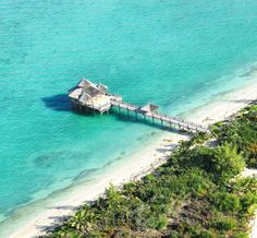 an aerial view of a beach and pier in the middle of the ocean with palm trees on both sides