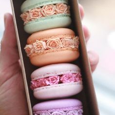 a box filled with macaroons covered in pink and green frosting