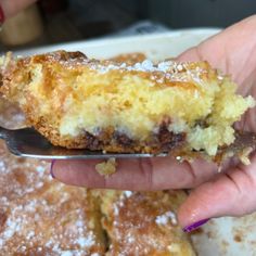 a close up of a person holding a piece of cake on a plate with a fork