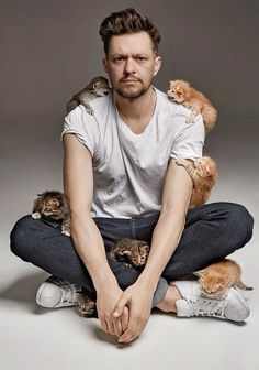 a man sitting on the floor holding two cats