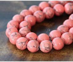 a close up of a necklace on a wooden surface with beads in the shape of balls