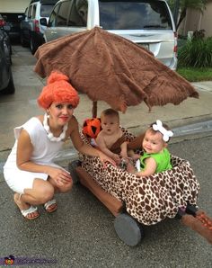 two women and a baby are sitting on a bench with an umbrella over their heads