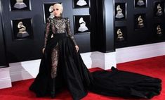 lady in black gown standing on red carpet with many heads and hands behind her back