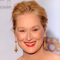 a smiling woman with red lipstick and gold earrings