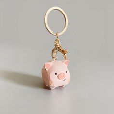 a pink pig keychain sitting on top of a white table next to a gray wall