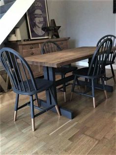 a wooden table with four chairs under a stair case