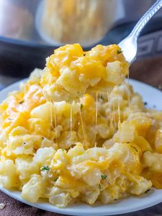 crockpot cheesy potatoes on a white plate with a spoon in it