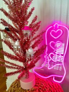 a pink neon sign sitting on top of a table next to a vase filled with flowers