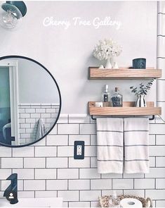 a bathroom with white tile and wooden shelves on the wall, along with a round mirror that says cherry tree gallery