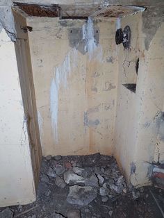 an unfinished bathroom with no shower curtain and rocks on the ground in front of it