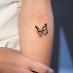 a woman's arm with a small butterfly tattoo on the left side of her arm