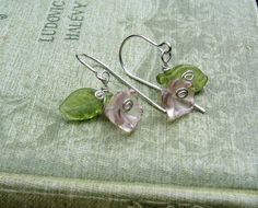 "These are cute little purple Czech glass flowers that we swirled some sterling silver tendrils around and added a peridot green colored Czech glass leaf. All the wire including the ear wires are sterling silver. The entire earring measures about 1\" (2.5cm) from the top of the ear wire to the bottom of the earring. The widest part across measures about 5/8\" (1.5cm). Check out our glass earrings/pendants section of our shop to see this design in other colors and our other glass flower designs a Whimsical Green Nickel-free Jewelry, Green Delicate Flower Jewelry, Nickel Free Green Jewelry For Spring, Nickel-free Green Jewelry For Spring, Whimsical Silver Flower Jewelry, Green Sterling Silver Flower Earrings, Whimsical Silver Flower-shaped Jewelry, Green Nickel-free Jewelry For Spring, Whimsical Green Flower Jewelry