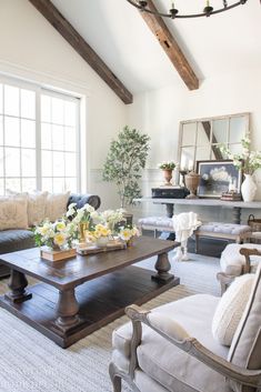 a living room filled with furniture and flowers on top of a coffee table in front of a fireplace