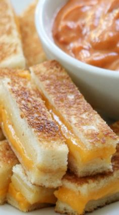 grilled cheese sandwiches on a plate with a small bowl of tomato sauce in the background