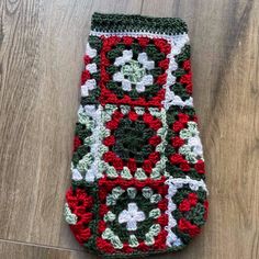 a crocheted granny blanket laying on top of a wooden floor