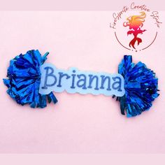 there is a name tag with blue pom poms attached to the back of it