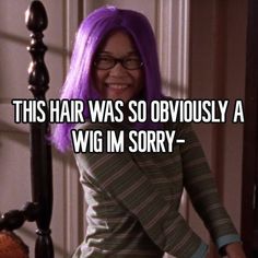 a woman with purple hair standing next to a bed and smiling at the camera text reads, this hair was so obviously a wig im sorry