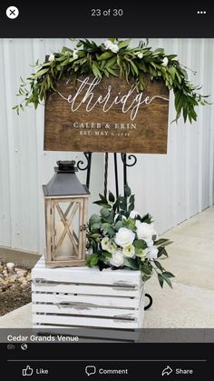 a wooden sign sitting on top of a white box next to a lantern and flowers