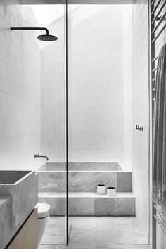 a bathroom with a glass shower door and white tile walls, along with two sinks