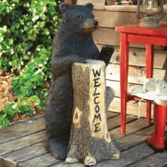 a statue of a bear sitting on top of a tree stump next to a red table