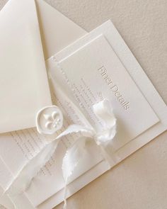 some white papers and buttons on top of each other with ribbons attached to the envelopes