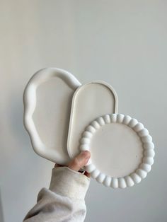 a person holding two white plates in their hand, one is shaped like an elephant