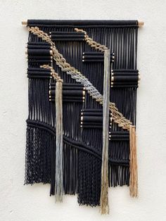 a wall hanging made out of black and white yarn with tassels on it