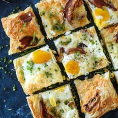 several square pieces of food with eggs and cheese on them sitting on a blue surface