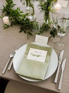 a place setting with napkins, silverware and greenery