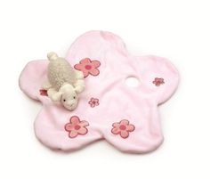 a stuffed animal laying on top of a pink flower shaped mat with flowers around it